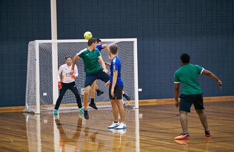 Two players contesting the ball near the goals in a men's futsal game