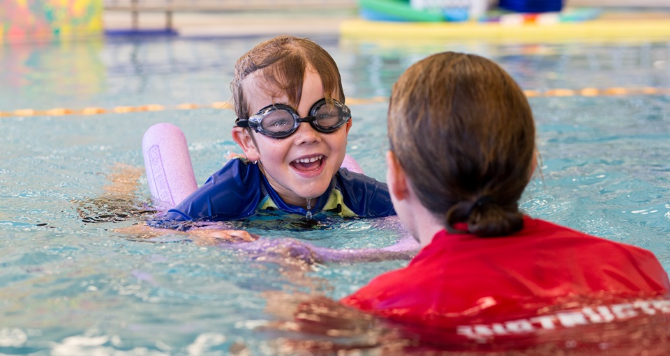 Child swimming with HA swim instructor