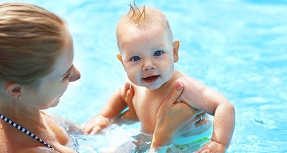 Mother in a pool holding her happy baby
