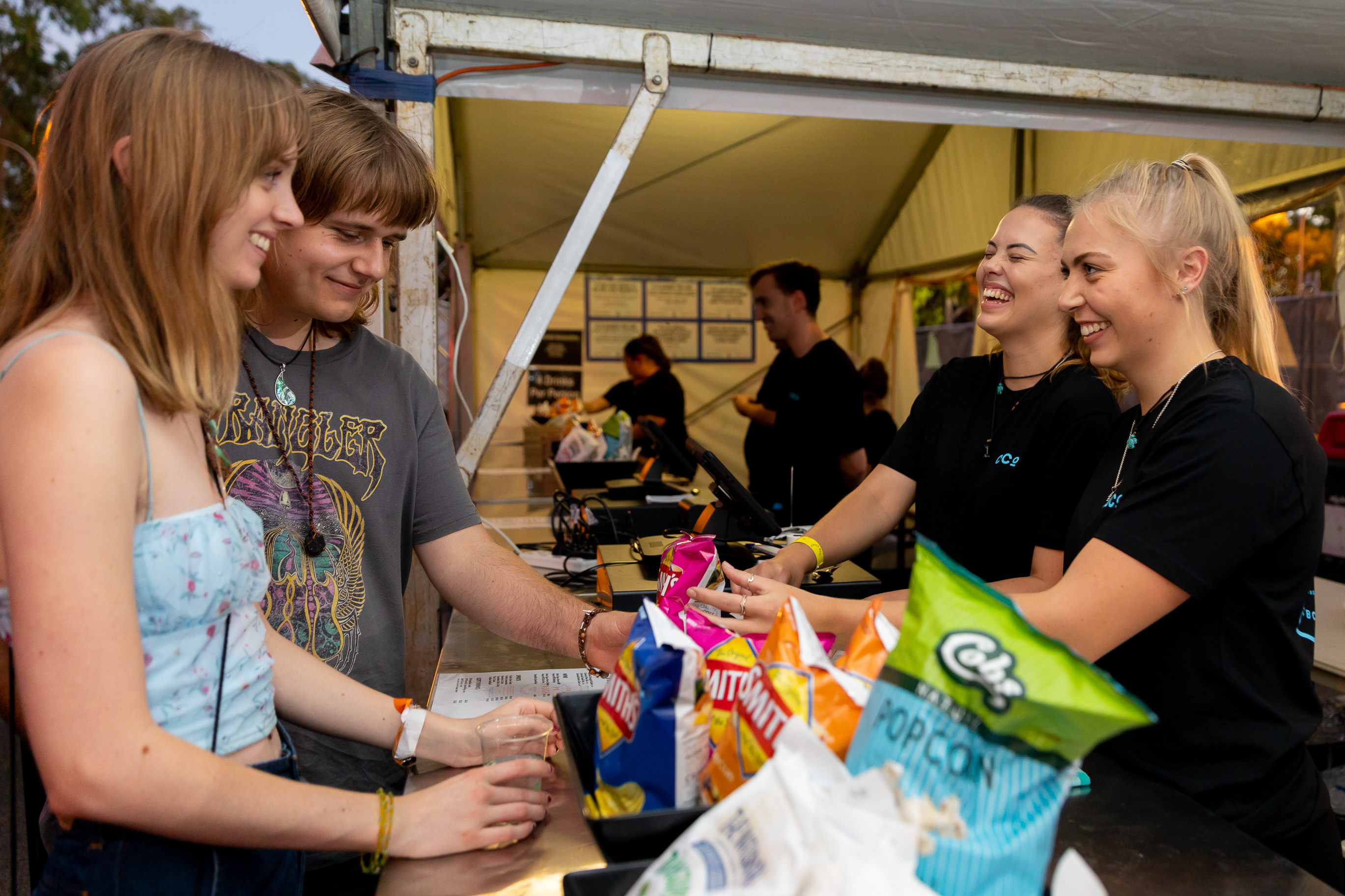 A photo of two cashiers selling food to two patrons
